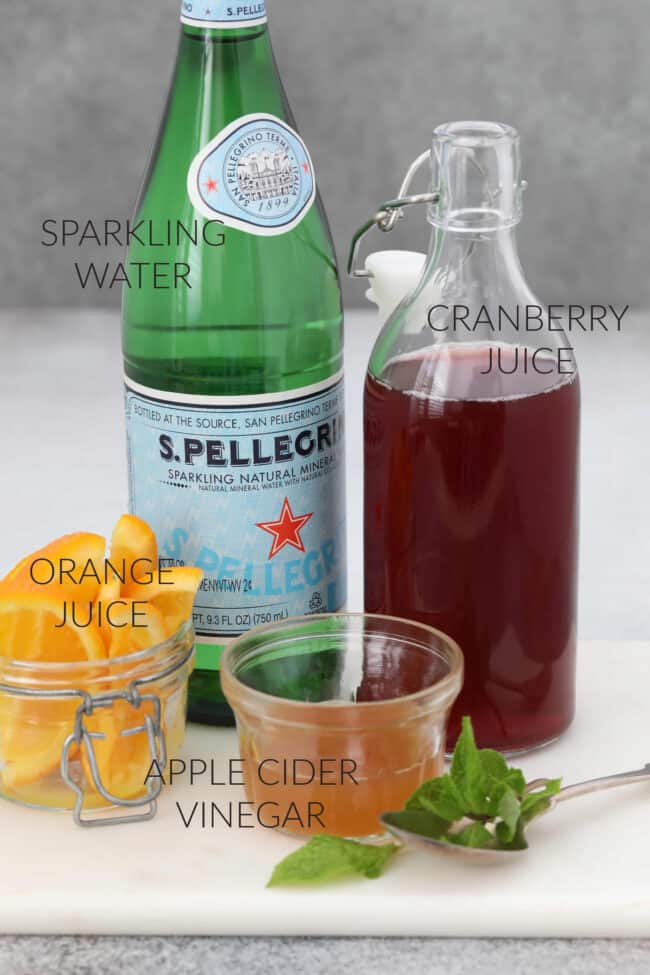 Bottle of sparkling water, orange wedges, apple cider vinegar for a detox drink. 