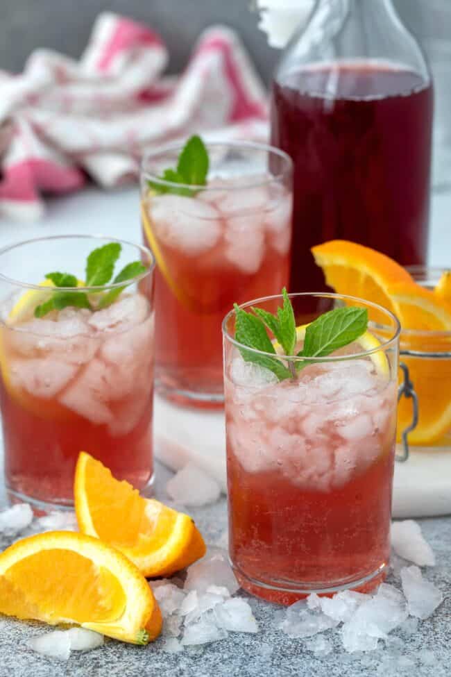 Three clear glasses filled with a pink drink.