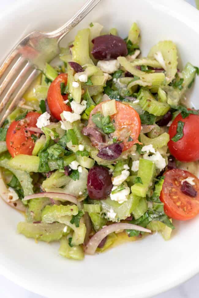 white bowl of salad with celery and tomatoes