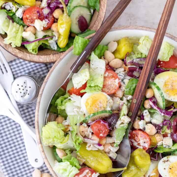 Two bowls of Italian chef salad tossed with gorgonzola dressing.