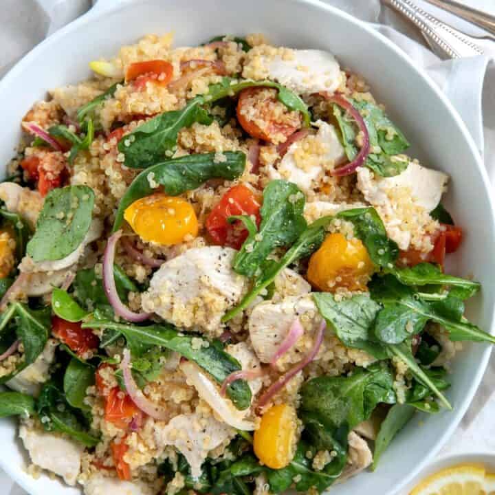 A white skillet with chicken and vegetables for quinoa chicken bowl