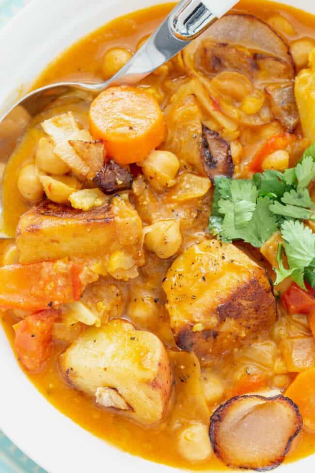 A white bowl of cooked legumes and vegetables.