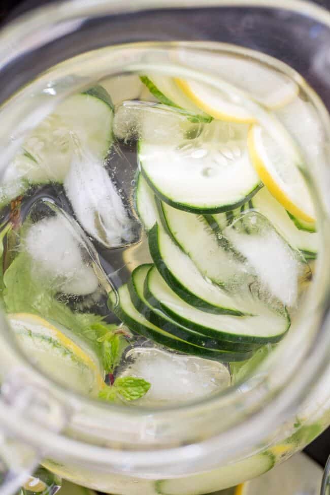 A clear glass pitcher with H2O and sliced fruit.