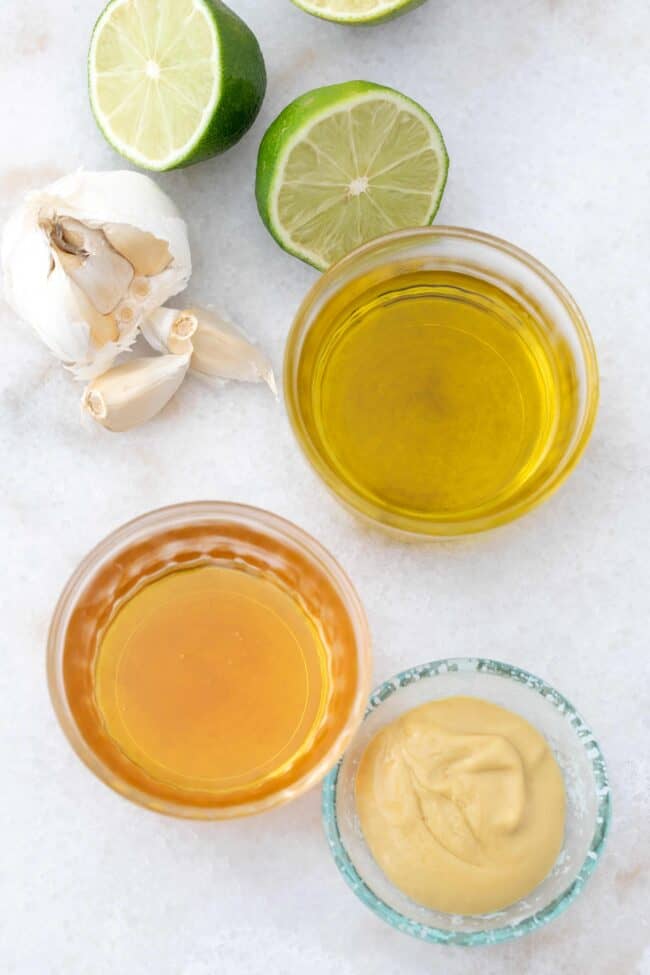 Three glass bowls filled with olive oil, honey and Dijon mustard.