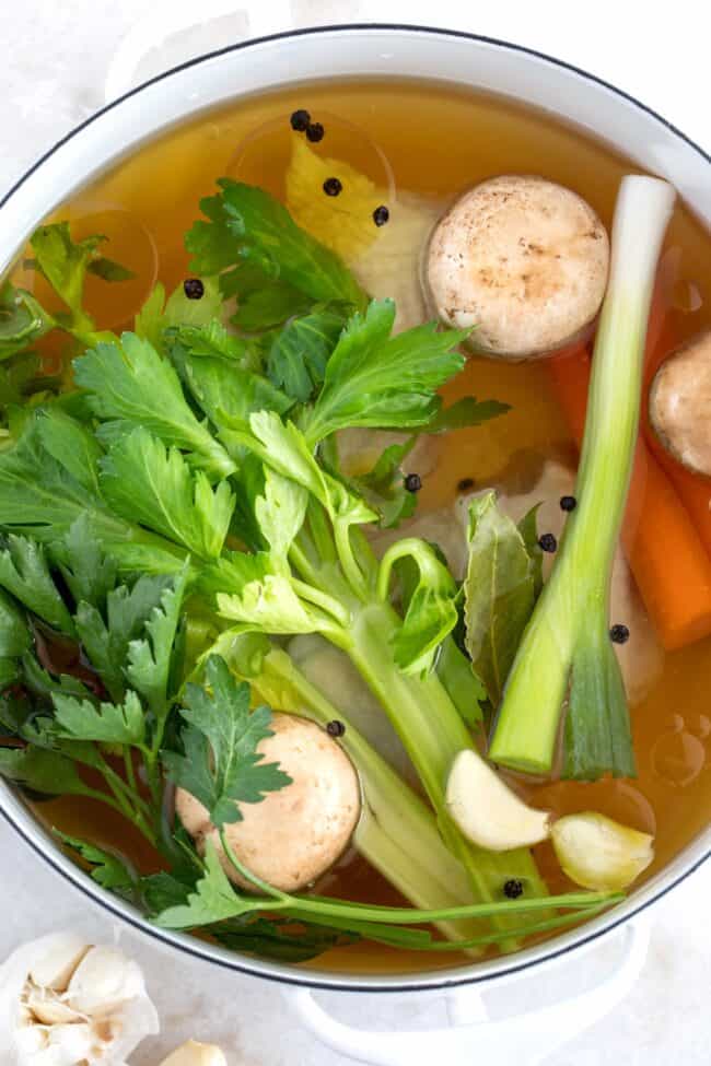 A white pot filled with vegetables in a broth