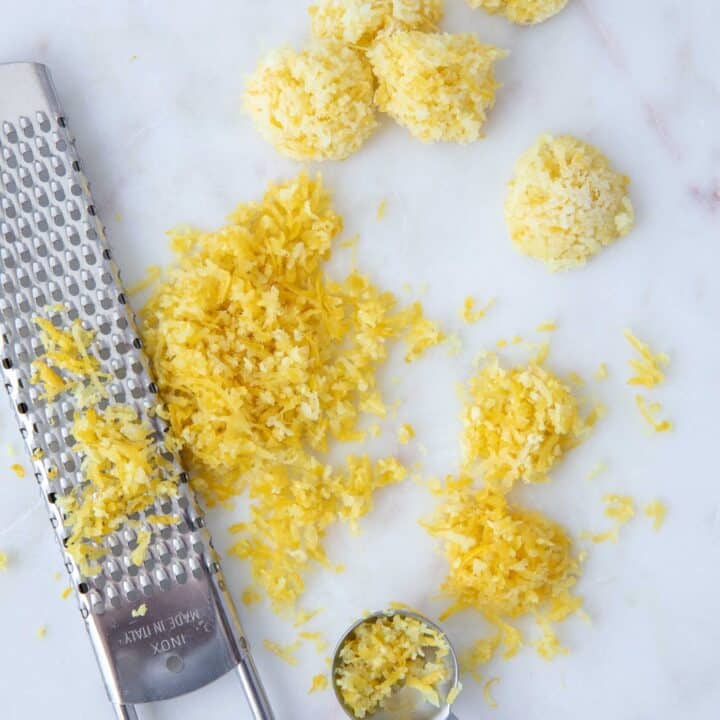 A metal zester next to a pile of lemon zest