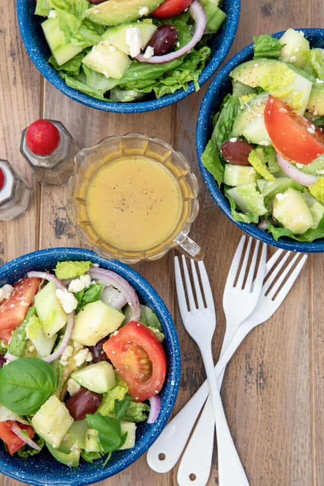 Blue bowls filled with avocado, tomatoes, red onion slices and kalamata olives