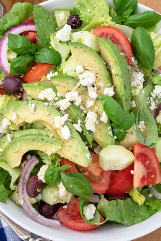 white bowl of Romaine lettuce salad with avocado, tomatoes and onion