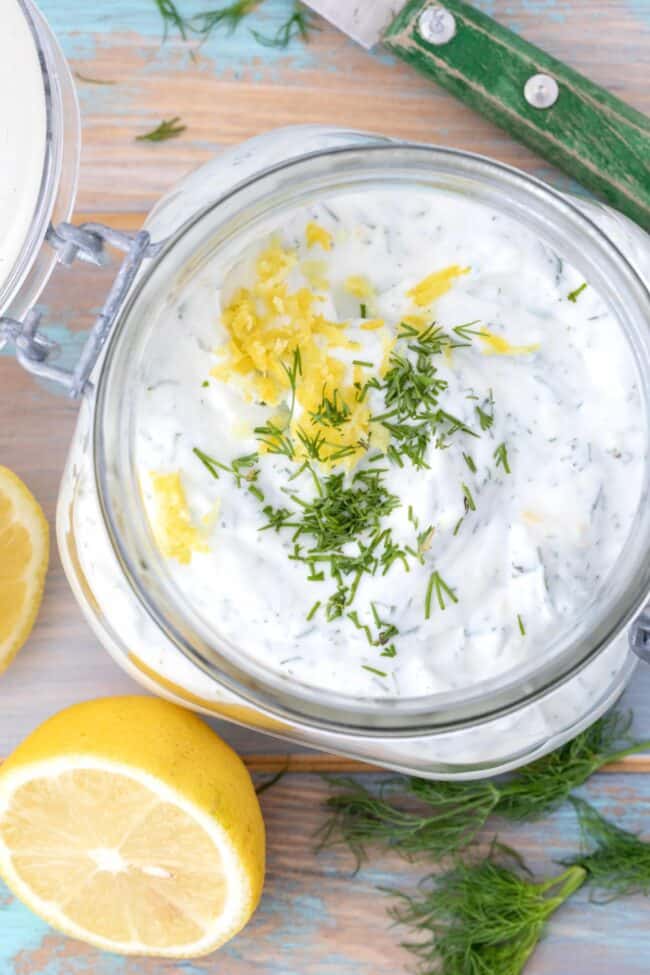 A clear mason jar filled with lemon dill sauce.