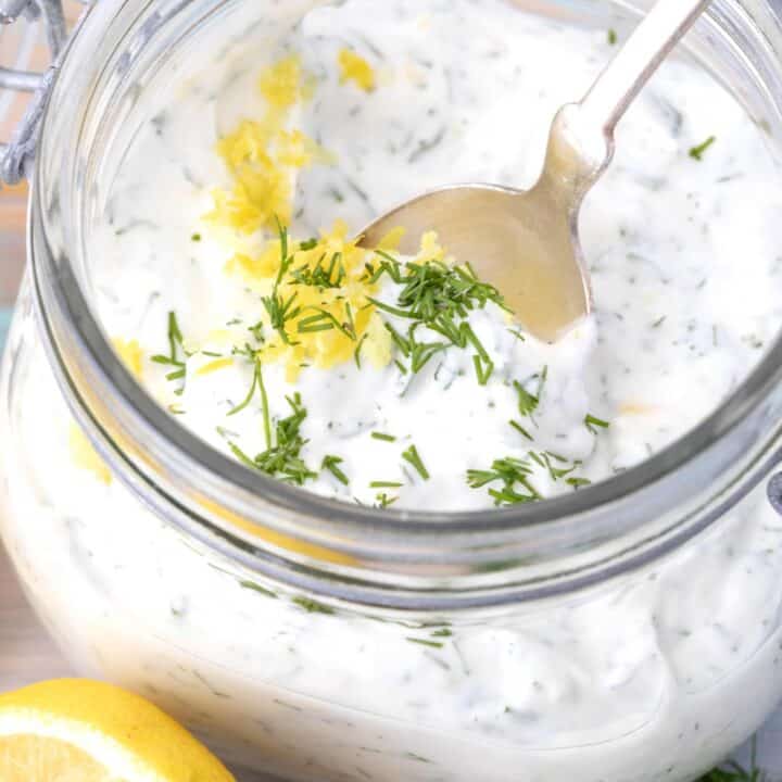 A clear mason jar filled with lemon dill sauce.