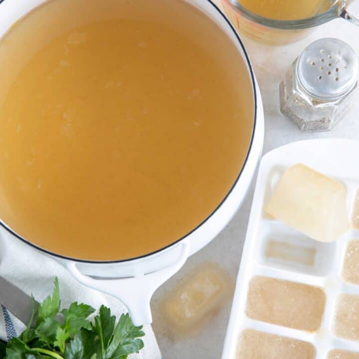white pot of chicken broth with ice cube tray filled with frozen broth