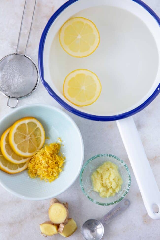 A white pot of water with lemons.