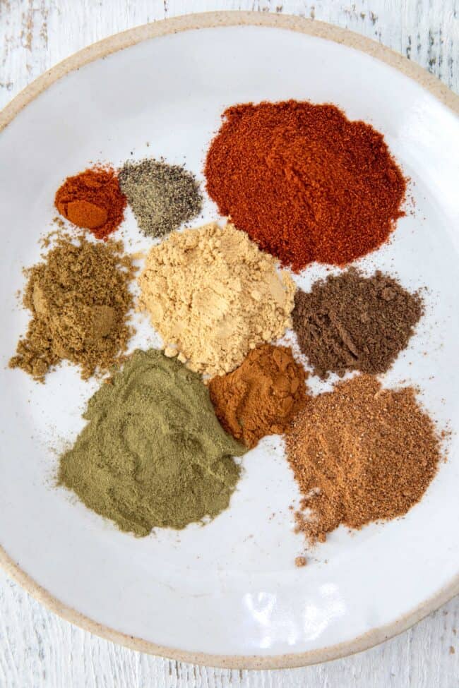 A white plate of different dried spices.
