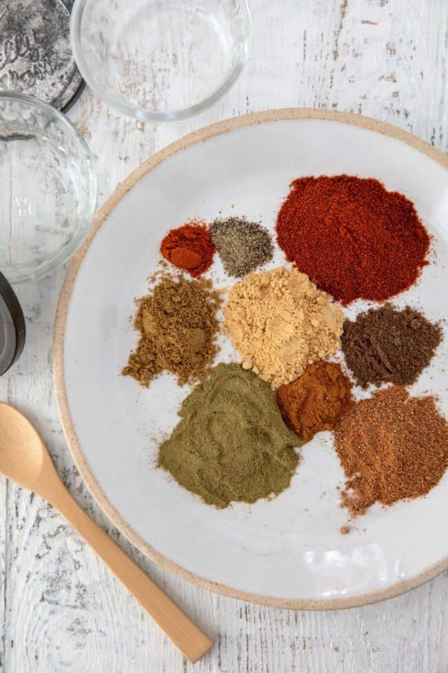 A white plate of different spices for Shawarma spice blend.