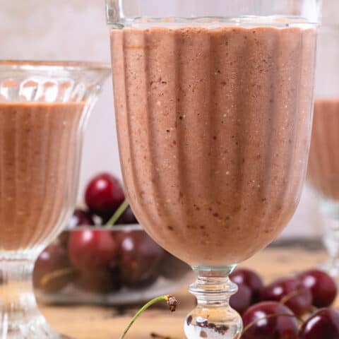 Three glasses of oat smoothie with cherries and cocoa.