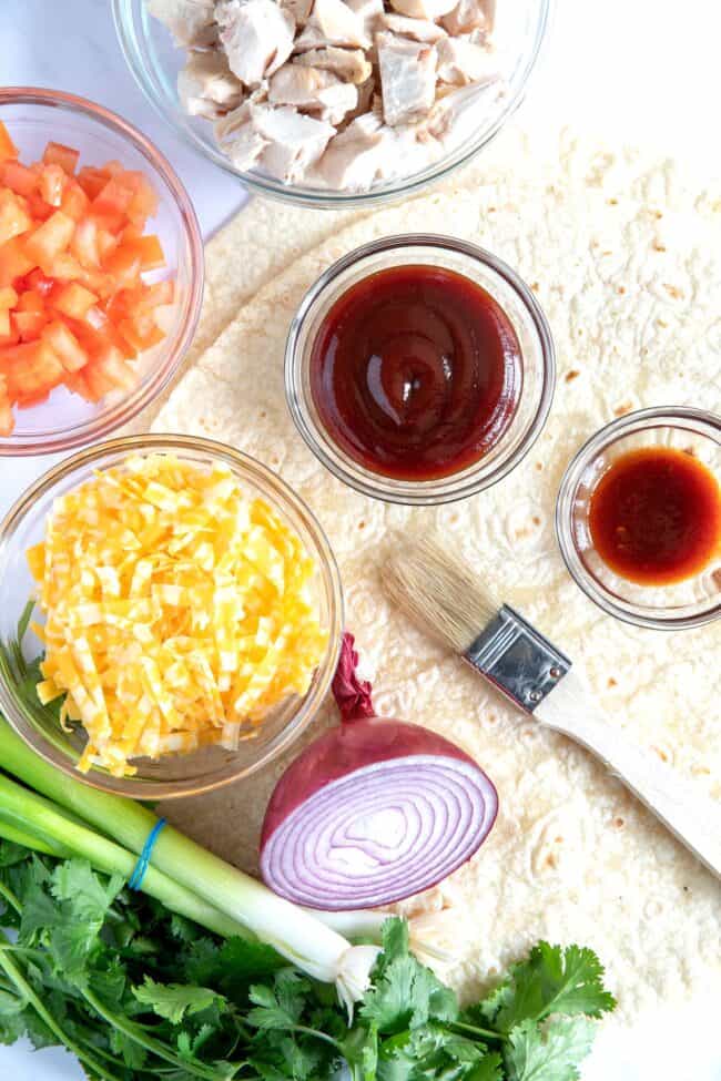 Clear glass bowls filled with sauce, cheese and tomatoes.