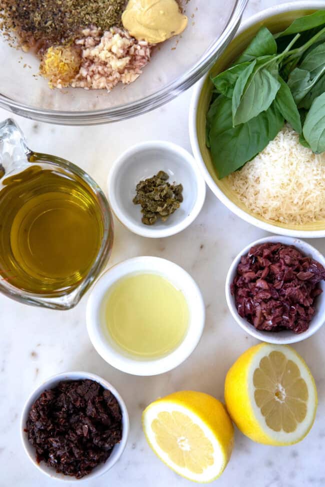 Various bowls filled with Greek salad dressing ingredients.