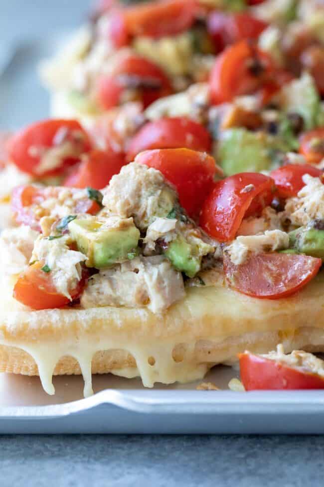 A silver colored tray of tuna melt open faced sandwiches.