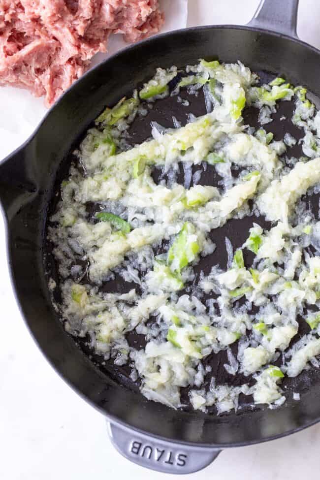 cast iron skillet cooking grated onions and bell pepper