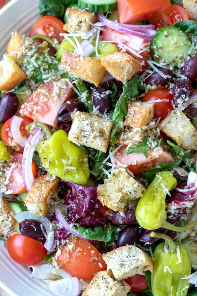 A white bowl with tossed Italian green salad.