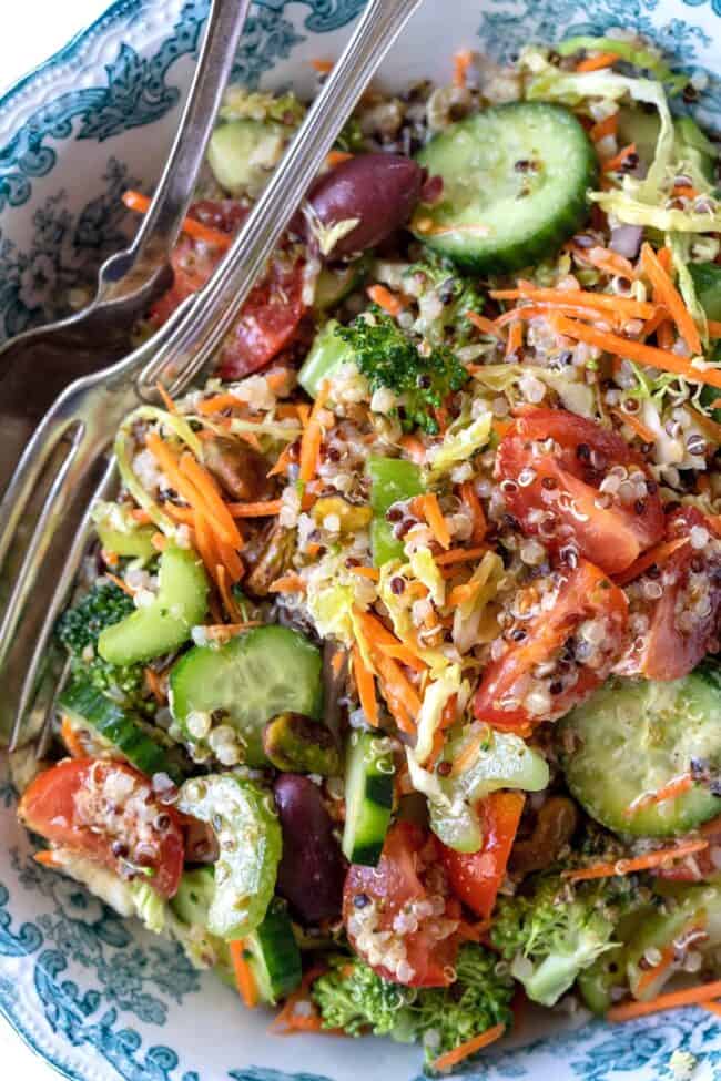A blue and white bowl filled with tri color quinoa salad. A fork rests in the bowl.