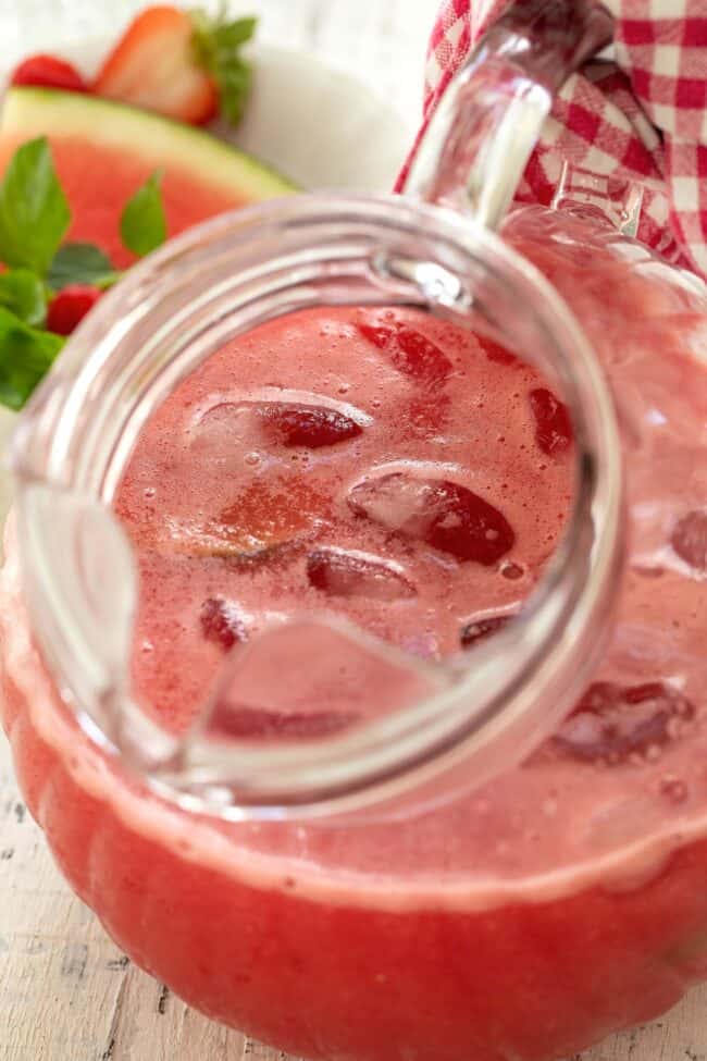 A clear glass pitcher of fresh blended fruit.