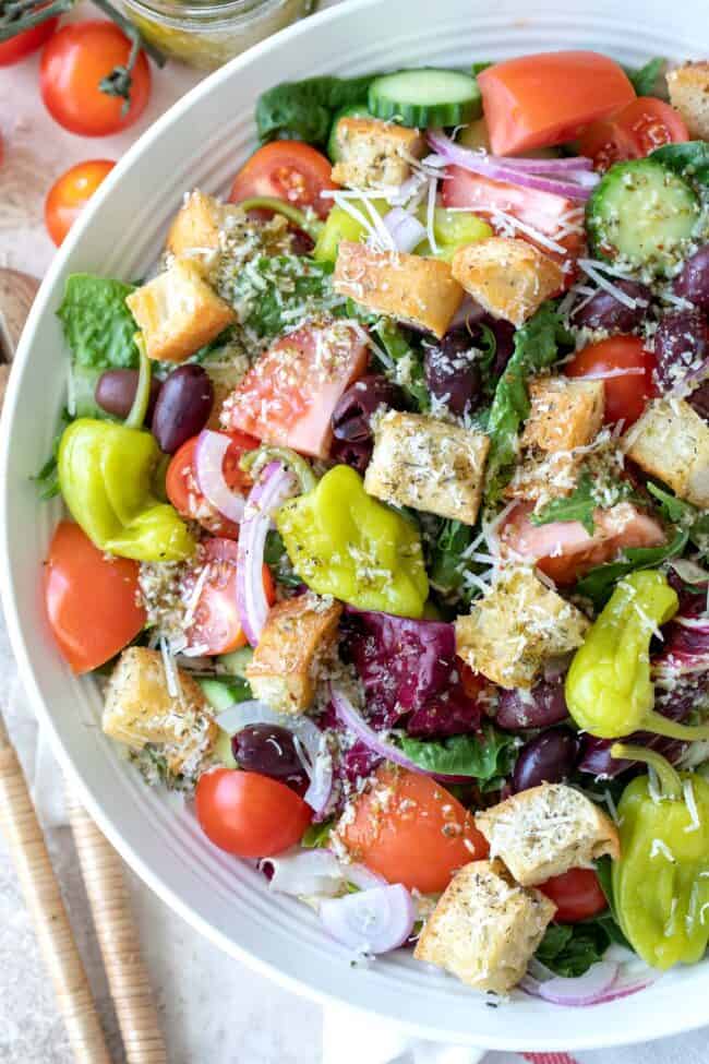 A white bowl filled with tossed greens and vegetables.