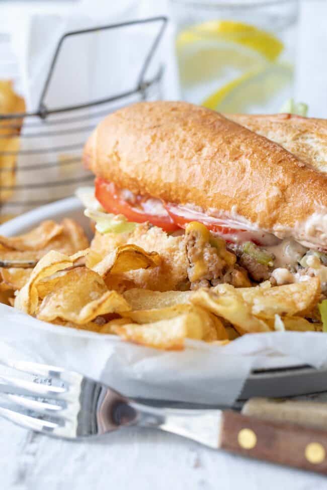 white plate with ground turkey and cheese sandwich on a French roll and potato chips