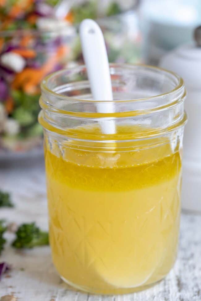 A clear glass mason jar filled with lemon vinaigrette.