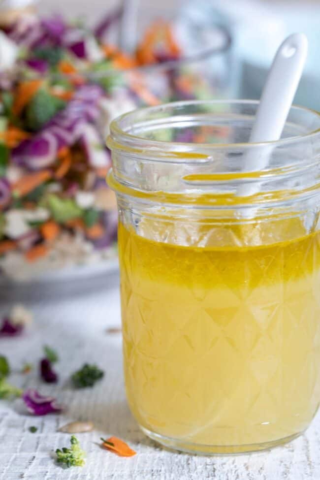 A mason jar filled with lemon ginger and honey (ginger dressing)and a white spoon