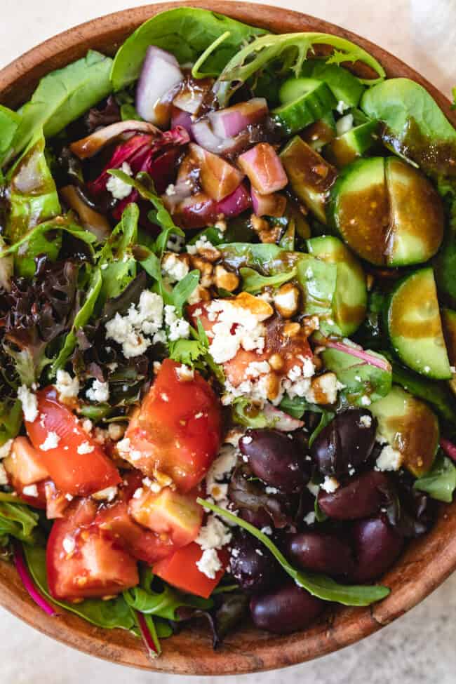 A tossed green salad with tomatoes, olives, cucumbers and Feta cheese tossed with homemade balsamic vinaigrette dressing..