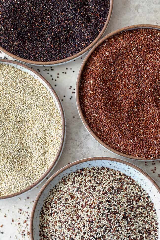 Four bowls of different types of uncooked quinoa.