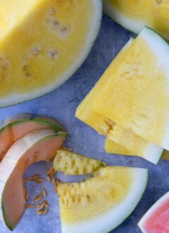 Large cut pieces of yellow watermelon next to slices of cantaloupe and red watermelon