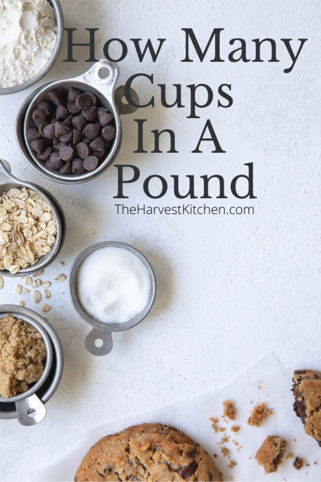 vintage measuring cups filled with flour, sugar, oats, and chocolate chips. A chocolate chip cookie sits next to the measuring cups.