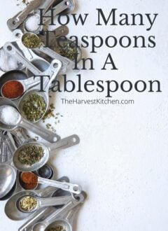several different sizes of measuring spoons scattered and filled with different herbs and spices