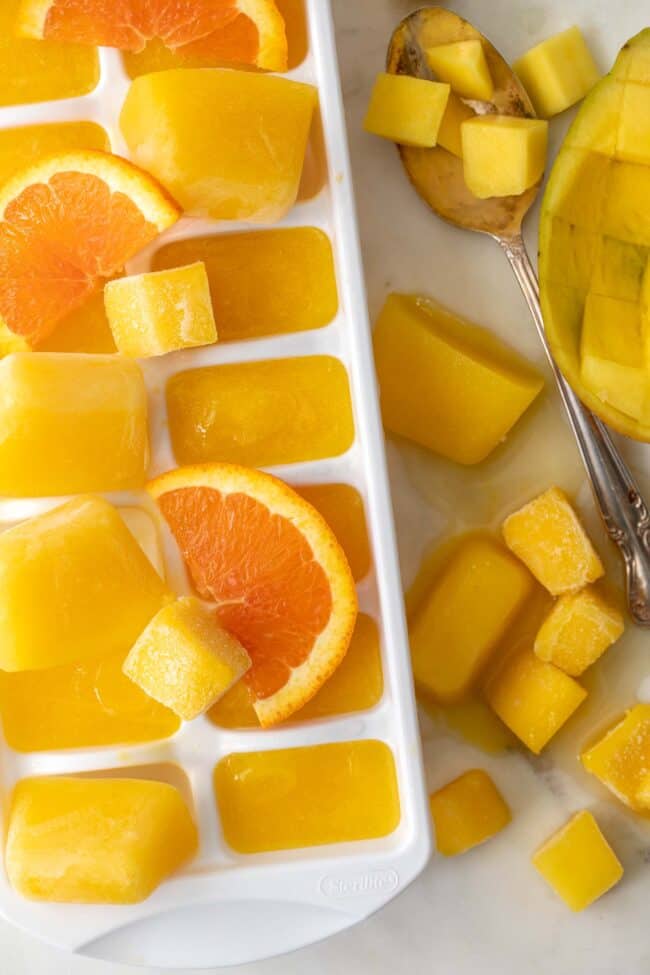 white ice cube tray filled with mango nectar juice ice cubes.