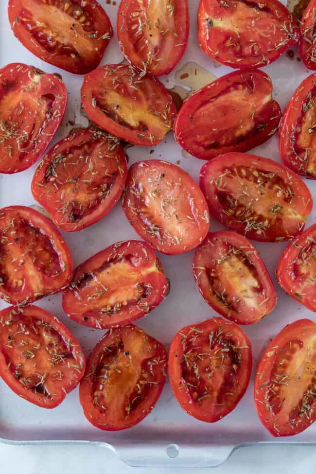 Tomatoes cut in half on a cookie sheet.