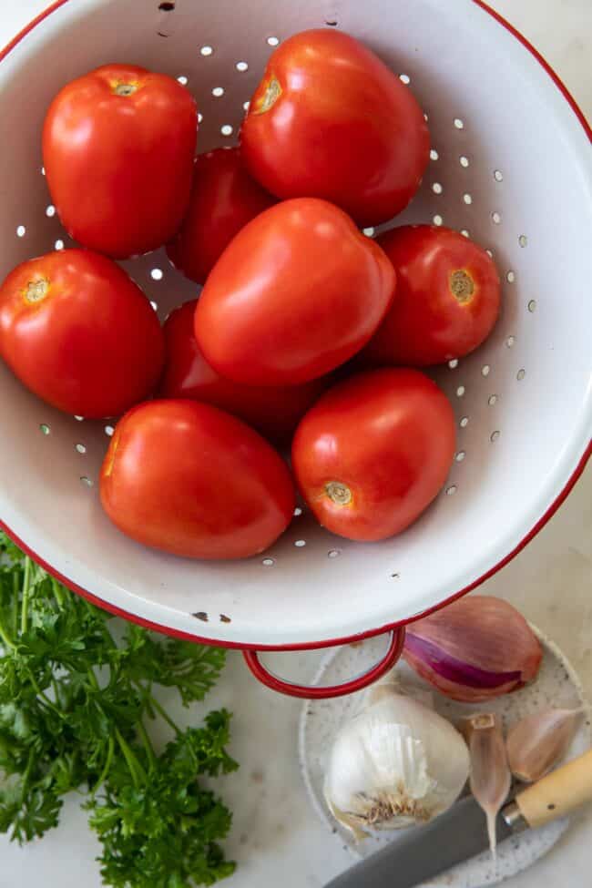 White colander filled with Plum tomatoes.