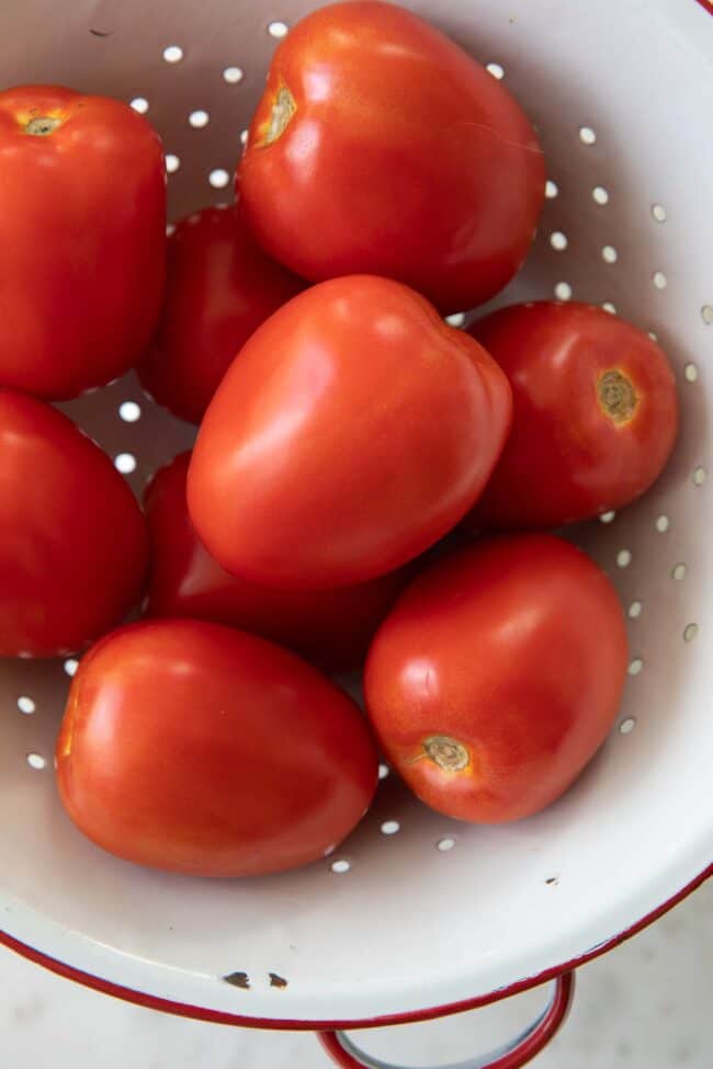 A white colander filled with tomatoes