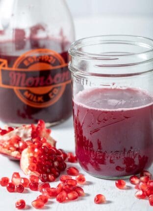 A glass bottle and mason jar filled with pomegranate juice