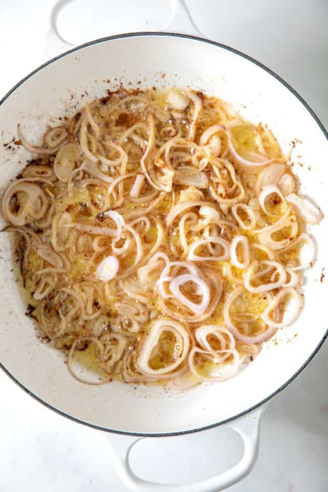A white skillet with fried shallots in it.