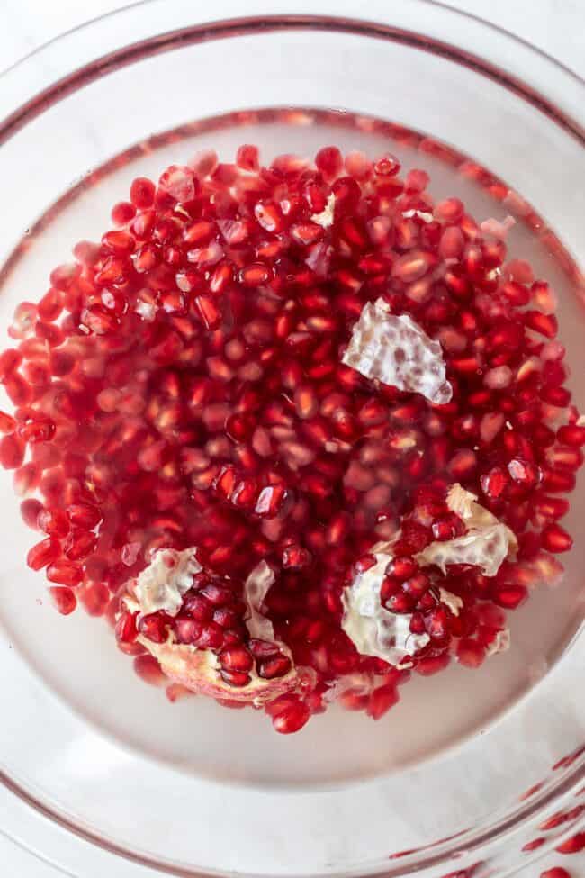 A clear glass bowl filled with water and red arils.