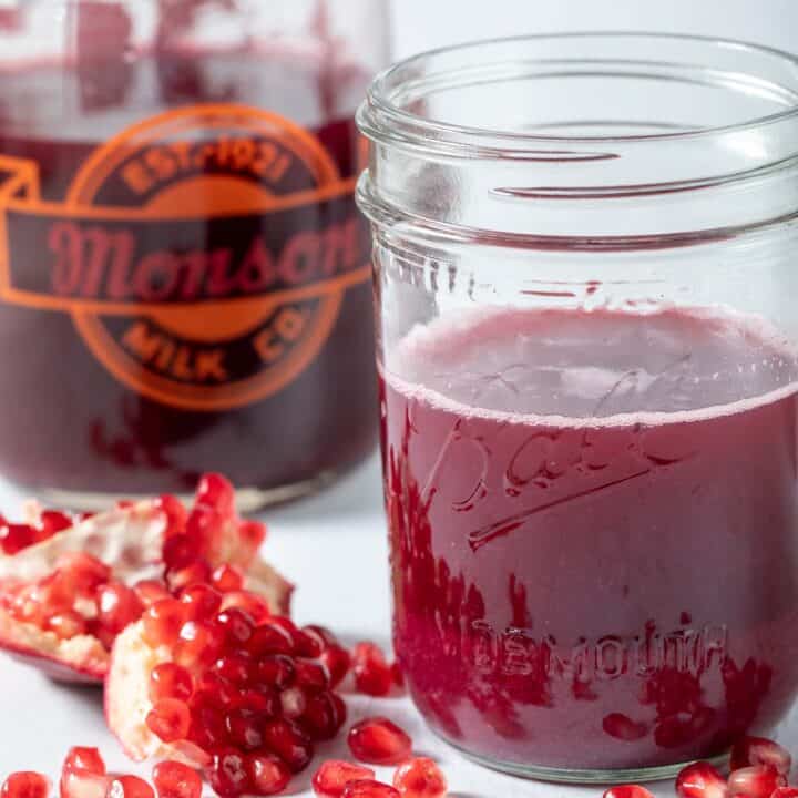 a glass pitcher and mason jar filled with pomegranate juice