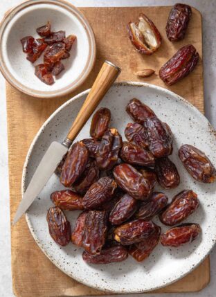 White plate filled with dates. A knife sits across the plate.