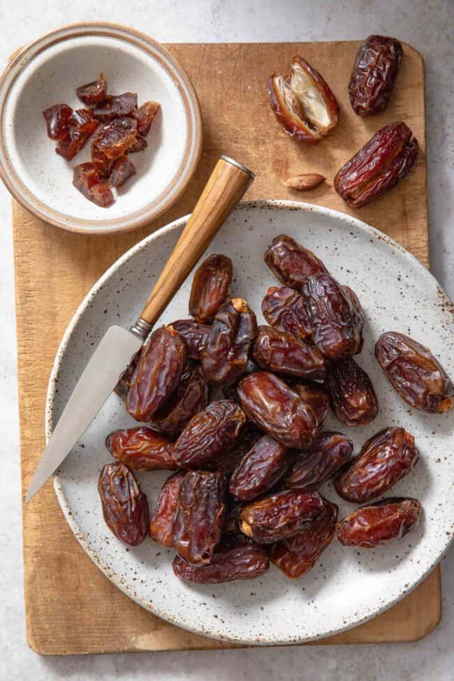 White plate filled with dates. A knife sits across the plate.