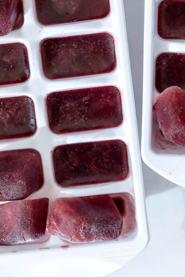 White ice cube tray filled with purple pomegranate elderberry ice cubes.
