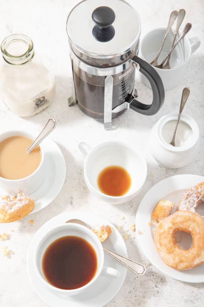 White coffee cups with a French press coffee maker and a plate of donuts for the measurements how many cups in a pint