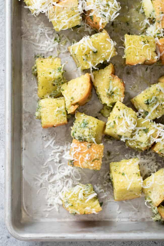An aluminum cooking sheet filled with basil pesto croutons.