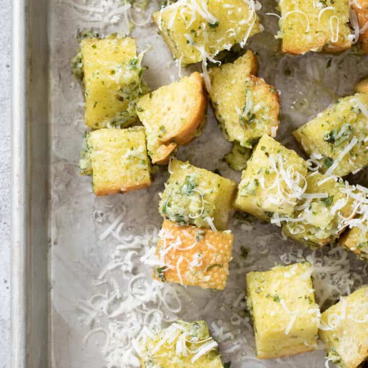 An aluminum cookie sheet filled with basil pesto croutons (Italian croutons).