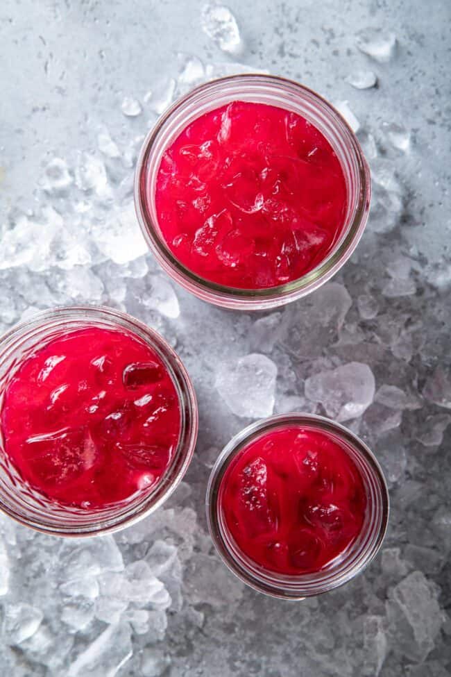 Three clear drinking glasses filled with fresh root vegetable liquid.